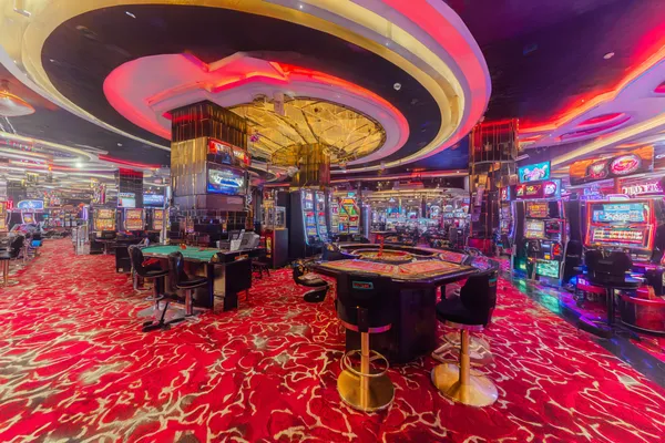 Un gros plan sur des pièces dorées tombant autour d'une roulette en mouvement, représentant l'action immersive des jeux de casino KWANZA.