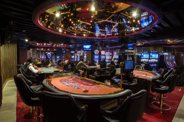 Une femme sourit en jouant en ligne sur son ordinateur portable au milieu d'éléments de casino lumineux, illustrant la collection variée de jeux proposée par KWANZA.