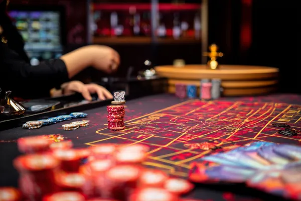 Une roulette lumineuse entourée de jetons symbolise les jeux en direct et les formats instantanés disponibles sur KWANZA.